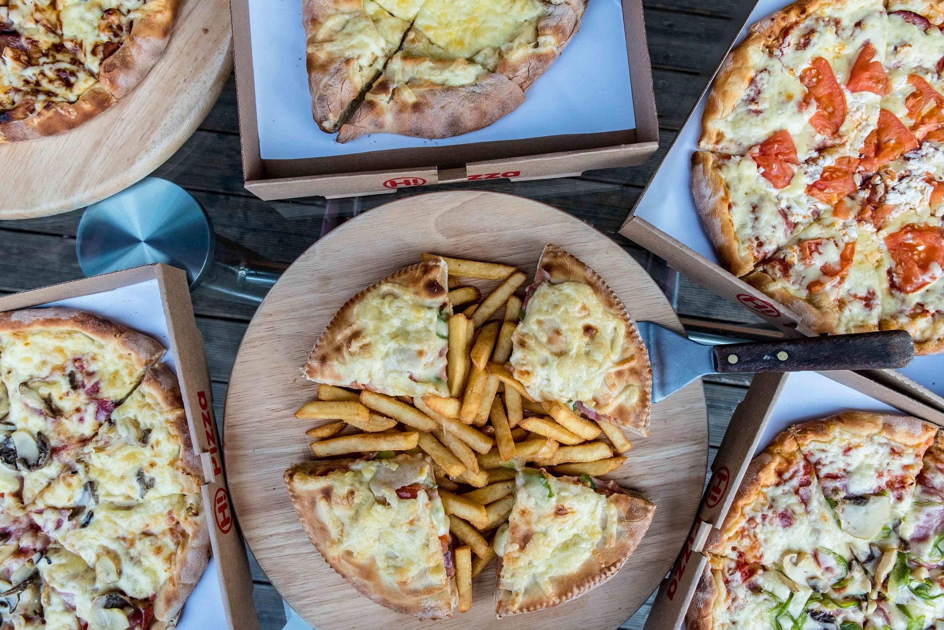 Hi Pizza pizzas on a wooden table, seen from above